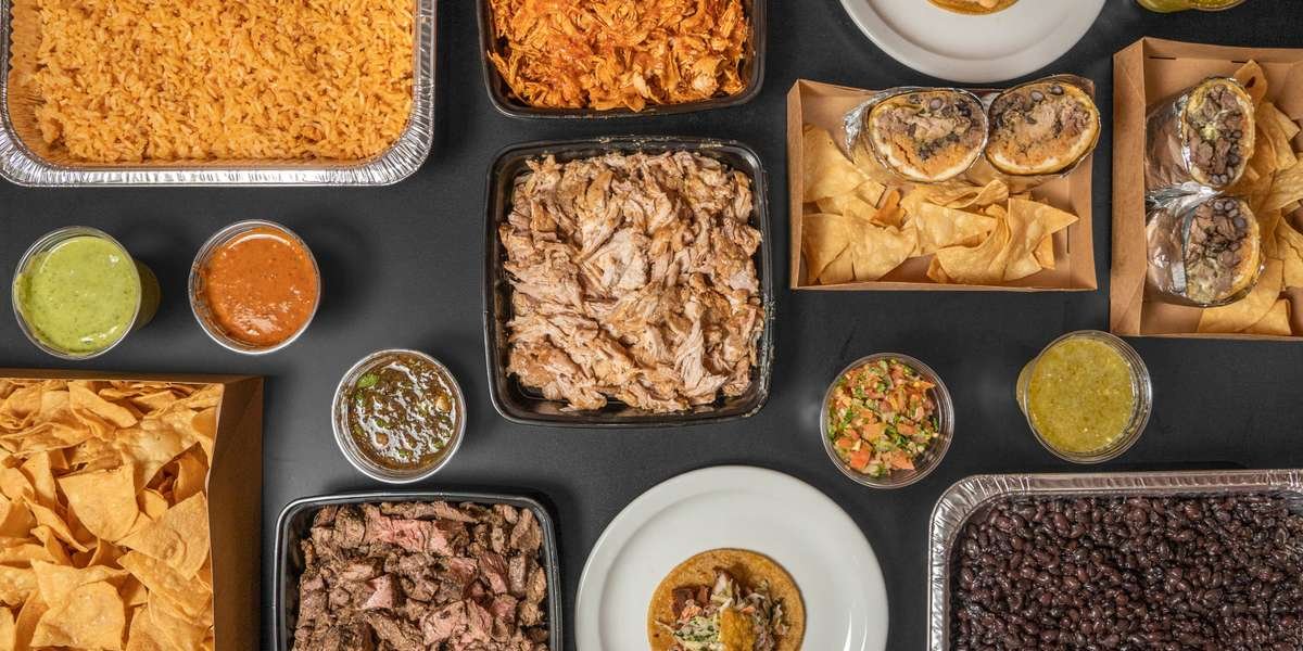 A catering spread of meats, tortillas, rice, beans and salsas