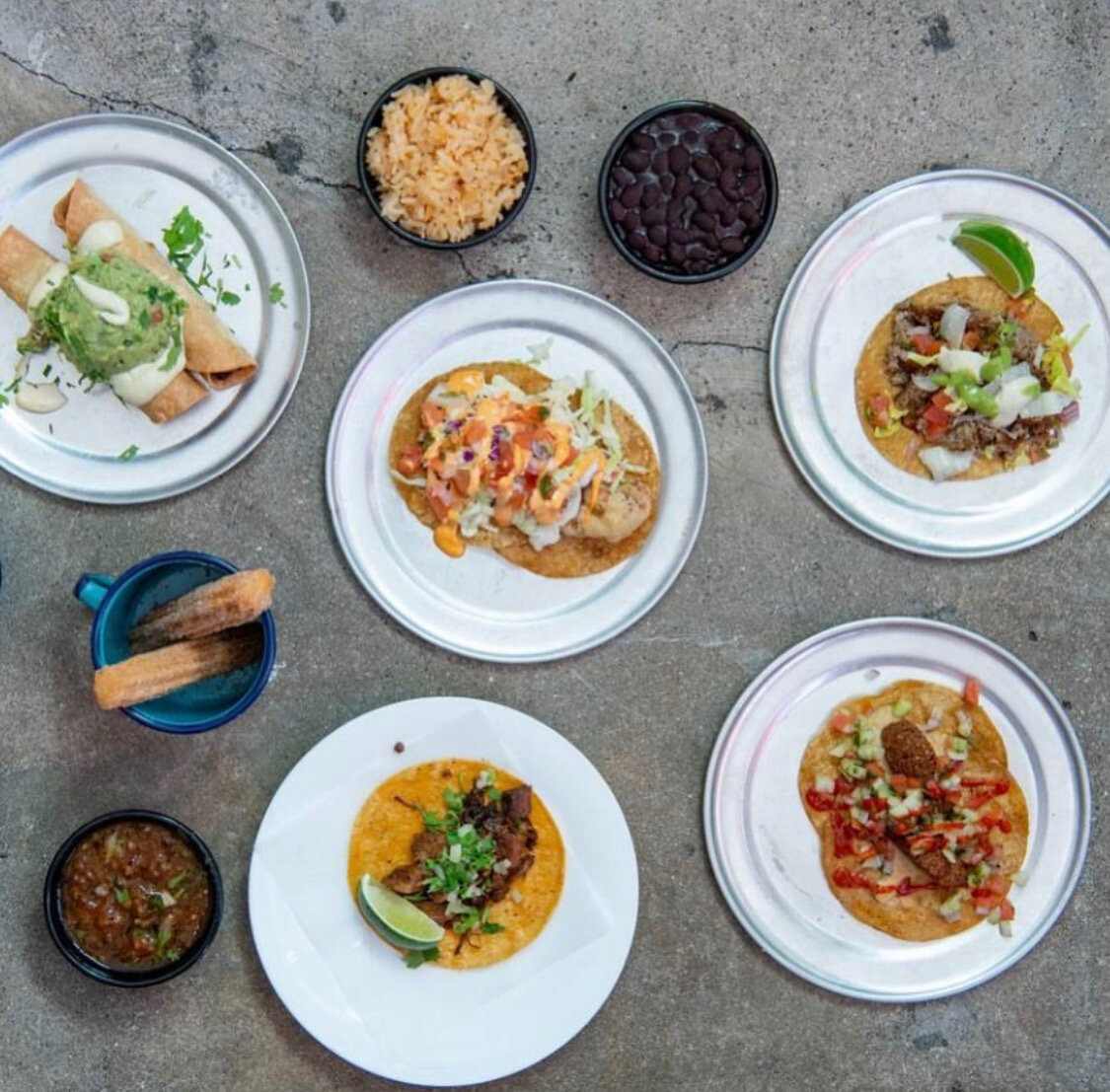 An overhead spread of Otro Día tacos with rice, beans, lime and salsa